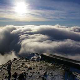 Image from the top of Snowdon Clouds lower down in the distance and the sun shinning bright.