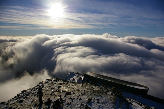 Image from the top of Snowdon Clouds lower down in the distance and the sun shinning bright.